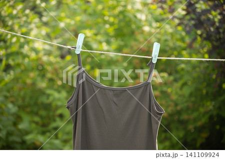 Tshirt hanging on clothesline outdoor minimal home laundry drying concept Tshirt hanging on clothesline outdoor minimal home laundry drying concept 141109924