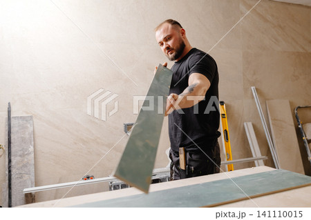 Construction worker checking large ceramic tile during renovation works Construction worker checking large ceramic tile during renovation works 141110015