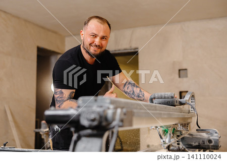 Construction worker cutting ceramic tiles using professional machine Construction worker cutting ceramic tiles using professional machine 141110024