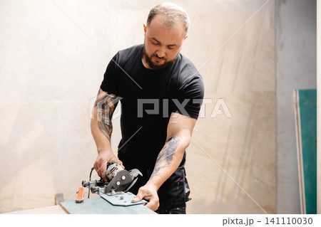 Construction Worker Using Tile Saw Cutting Ceramic Tiles Construction Worker Using Tile Saw Cutting Ceramic Tiles 141110030