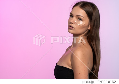 Young woman applying hydrogel patches for under-eye care, focusing on beauty, hydration, and facial treatment Young woman applying hydrogel patches for under-eye care, focusing on beauty, hydration, and facial treatment 141110132