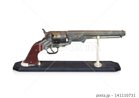 side view two antique and old brass guns with a brown leather grip, placed on a wooden stand against a white background 141110731