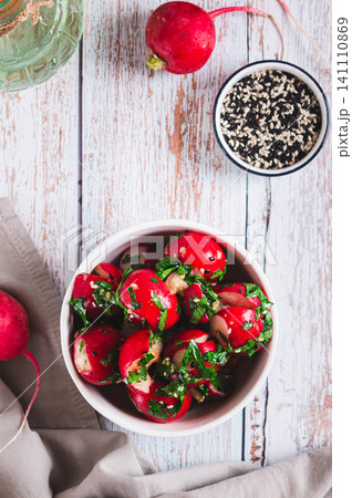 Fresh smashed radishes marinated with herbs and sesame seeds in a bowl top and vertical view Fresh smashed radishes marinated with herbs and sesame seeds in a bowl top and vertical view 141110869