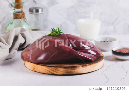 Raw whole pork liver on a wooden board on the table 141110893
