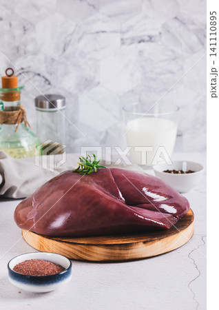 Raw whole pork liver on a wooden board on the table vertical view Raw whole pork liver on a wooden board on the table vertical view 141110895