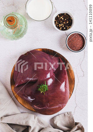Fresh beef liver on a cutting board on the table top and vertical view Fresh beef liver on a cutting board on the table top and vertical view 141110899