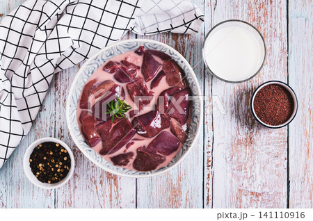 Raw pork liver soaked in milk in a bowl on the table top view Raw pork liver soaked in milk in a bowl on the table top view 141110916