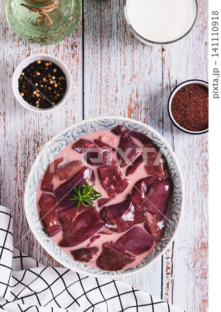 A bowl of raw chopped liver marinated in milk on the table top and vertical view A bowl of raw chopped liver marinated in milk on the table top and vertical view 141110918