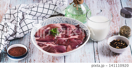 Raw pork liver soaked in milk in a bowl on the table web banner Raw pork liver soaked in milk in a bowl on the table web banner 141110920