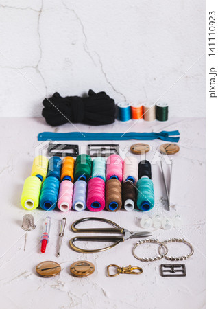 A set of spools of multi-colored threads and sewing supplies on a table vertical view A set of spools of multi-colored threads and sewing supplies on a table vertical view 141110923