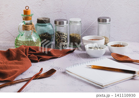 A notebook and pen for writing down recipes, spoons and spices on the kitchen table A notebook and pen for writing down recipes, spoons and spices on the kitchen table 141110930