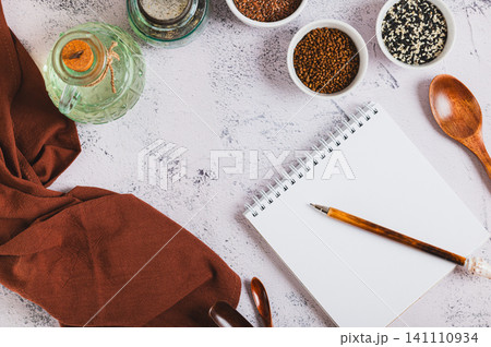 A notebook and pen for writing down recipes, spoons and spices on the kitchen table top view A notebook and pen for writing down recipes, spoons and spices on the kitchen table top view 141110934