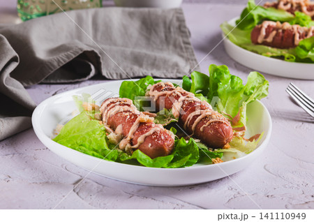 Grilled sausage with sauce and croutons on lettuce leaves on a plate on the table Grilled sausage with sauce and croutons on lettuce leaves on a plate on the table 141110949
