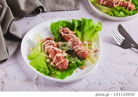 Caesar hot dog on lettuce leaves on a plate on the table Caesar hot dog on lettuce leaves on a plate on the table 141110950