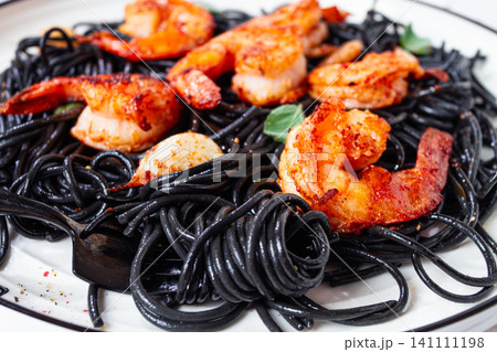 Black spaghetti with shrimp, on a white plate with a fork, on a striped napkin,marble background, homemade, no people, Black spaghetti with shrimp, on a white plate with a fork, on a striped napkin,marble background, homemade, no people, 141111198