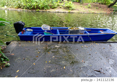 Blue boat moored by lake on wet concrete dock Blue boat moored by lake on wet concrete dock 141112136
