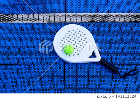 A padel racket and ball. on blue court A padel racket and ball. on blue court 141112524