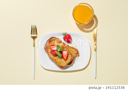 Brioche toasts with strawberries and honey on a plate on a yellow background Brioche toasts with strawberries and honey on a plate on a yellow background 141112536