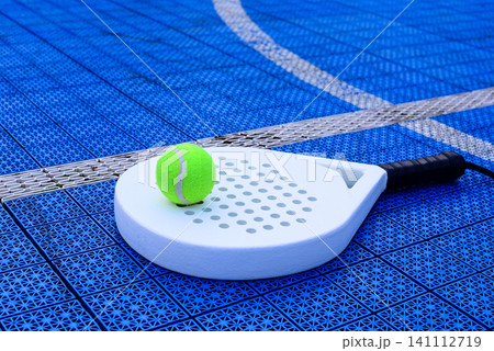 A padel racket and ball. on blue court A padel racket and ball. on blue court 141112719