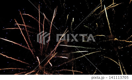 Bright fireworks burst across dark night sky with long sparkling trails in gold, pink, white, and blue, creating festive celebration atmosphere and dramatic glowing light Bright fireworks burst across dark night sky with long sparkling trails in gold, pink, white, and blue, creating festive celebration atmosphere and dramatic glowing light 141113705