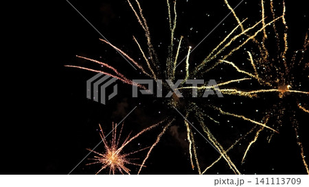 Golden and orange fireworks explode across dark night sky, sending sparkling trails and glowing embers in many directions for festive celebration, holiday event, and vivid Golden and orange fireworks explode across dark night sky, sending sparkling trails and glowing embers in many directions for festive celebration, holiday event, and vivid 141113709