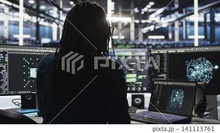 Data center technician arriving in office, working with AI visualization insights on computer to improve system health. Data center technician arriving in office, working with AI visualization insights on computer to improve system health. 141113761