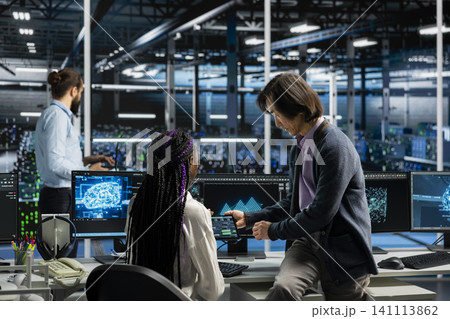 Server room manager teaching intern how to run AI prediction simulations, tracking performance. 141113862
