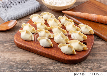 Freshly handmade raw uncooked Chinese dumplings Jiaozi arranged on wooden board Freshly handmade raw uncooked Chinese dumplings Jiaozi arranged on wooden board 141115380