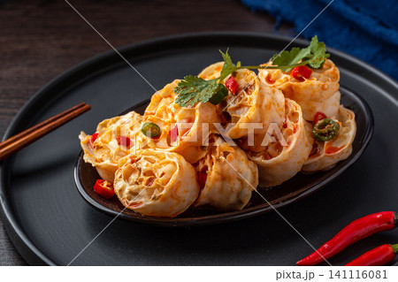 spicy cold wheat gluten noodles served on a black plate with red chili peppers, spicy cold wheat gluten noodles served on a black plate with red chili peppers, 141116081
