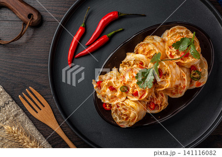 spicy cold wheat gluten noodles served on a black plate with red chili peppers, spicy cold wheat gluten noodles served on a black plate with red chili peppers, 141116082