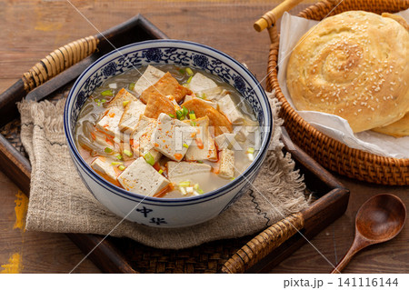 authentic Chinese breakfast tofu soup topped with chili flakes, served in a blue patterned bowl authentic Chinese breakfast tofu soup topped with chili flakes, served in a blue patterned bowl 141116144
