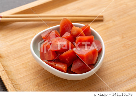 savory pickled carrot chunks in a white ceramic bowl on a wooden tray, Asian style marinated vegetable 141116179