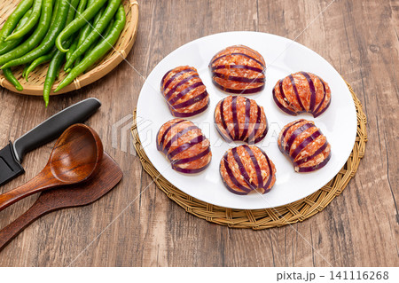 raw stuffed lantern eggplants with minced pork meat filling, prepared on a white plate on a wooden rustic table. Prepped ingredients for traditional Chinese cuisine. 141116268