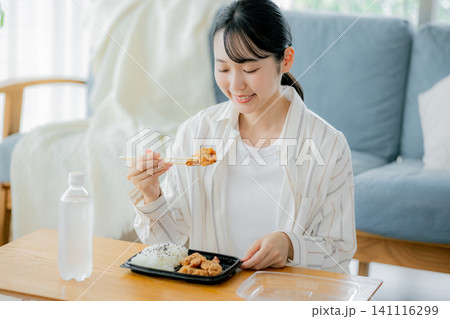 リビングでお弁当を食べる若い女性 リビングでお弁当を食べる若い女性 141116299