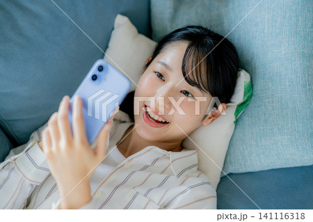 ソファでスマホを見る女性 141116318