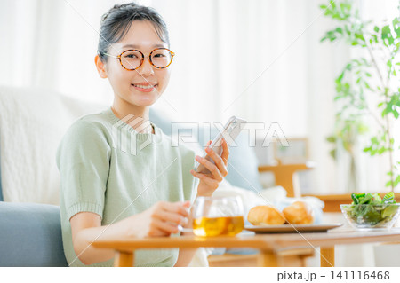 朝ごはんの時にスマホを見る若い女性 朝ごはんの時にスマホを見る若い女性 141116468