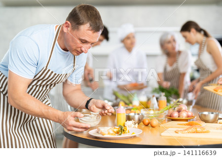 Adult man pouring sauce into dish at master class Adult man pouring sauce into dish at master class 141116639