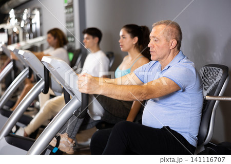 Aged man doing cardio workout on exercise bike in gym Aged man doing cardio workout on exercise bike in gym 141116707