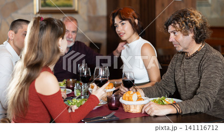 Large friendly family gathered at table to have lunch in restaurant Large friendly family gathered at table to have lunch in restaurant 141116712