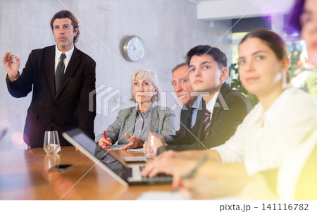 Man top manager standing and confidently speaking during corporate meeting using hand gestures Man top manager standing and confidently speaking during corporate meeting using hand gestures 141116782