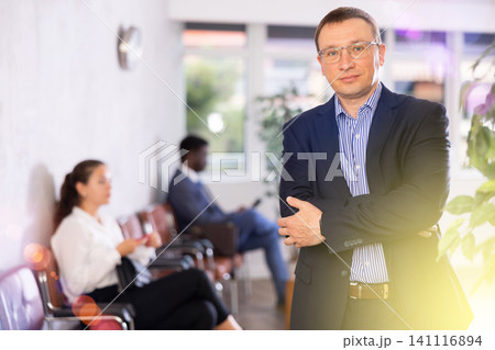 Confident middle-aged man standing with his back to waiting room Confident middle-aged man standing with his back to waiting room 141116894