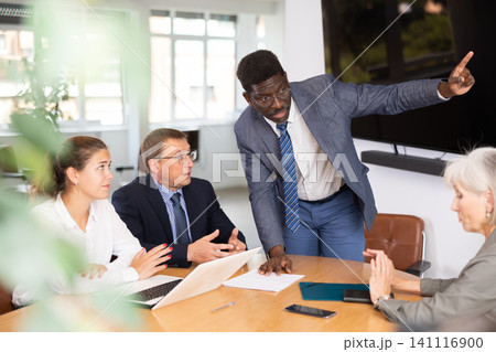 Angry middle-aged man shouting at his business partners sitting around table 141116900
