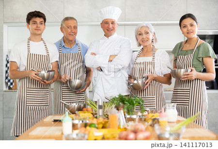 Group of cooks with utensils posing in kitchen Group of cooks with utensils posing in kitchen 141117013