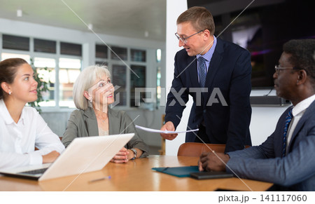 Middle-aged man head of department reports about success and sales growth at meeting. Middle-aged man head of department reports about success and sales growth at meeting. 141117060