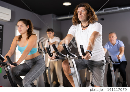 Sporty man working out on stationary bicycle in gym Sporty man working out on stationary bicycle in gym 141117079