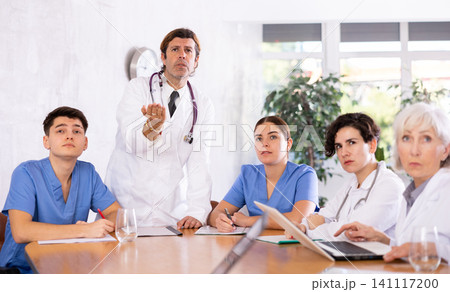 Medical staff during morning briefing in boardroom of clinic Medical staff during morning briefing in boardroom of clinic 141117200