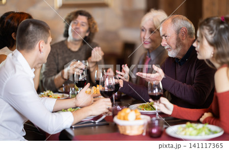 Family members enjoying warm conversation in restaurant Family members enjoying warm conversation in restaurant 141117365