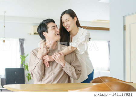 リビングで、男性の腕に手を回す若い日本人女性 リビングで、男性の腕に手を回す若い日本人女性 141117921