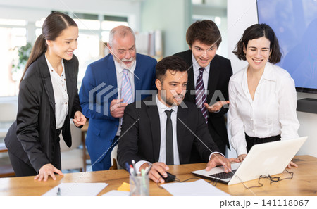 Group of business people discuss business strategies and planning work together, everyone looking at laptop by man and laughing in corporate office Group of business people discuss business strategies and planning work together, everyone looking at laptop by man and laughing in corporate office 141118067
