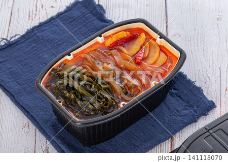 self-heating instant spicy hotpot with wide glass noodles and kelp knots on a blue napkin self-heating instant spicy hotpot with wide glass noodles and kelp knots on a blue napkin 141118070